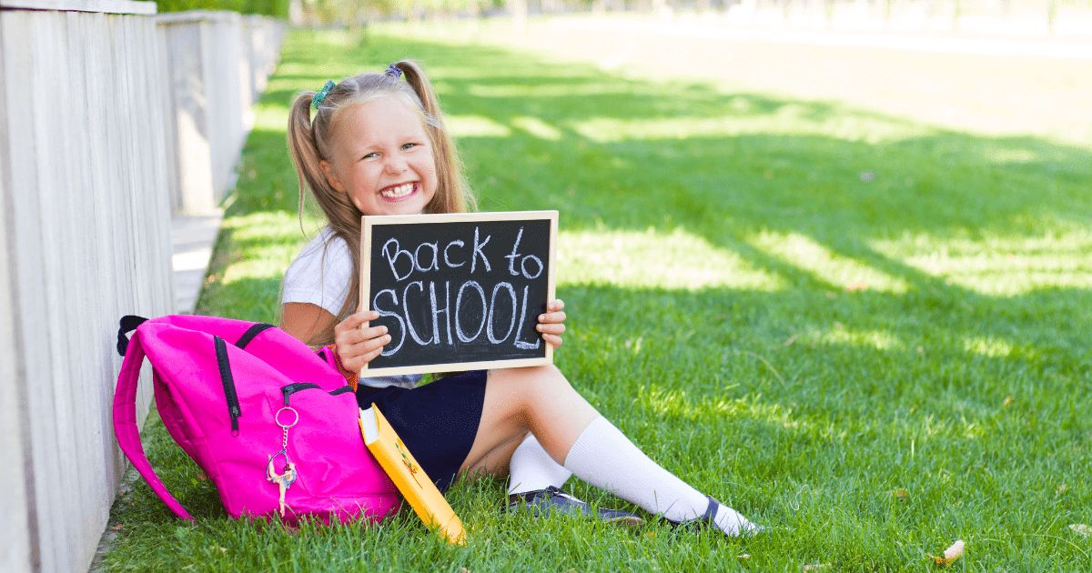 Girl with her backpack and a mini black board saying Back to School