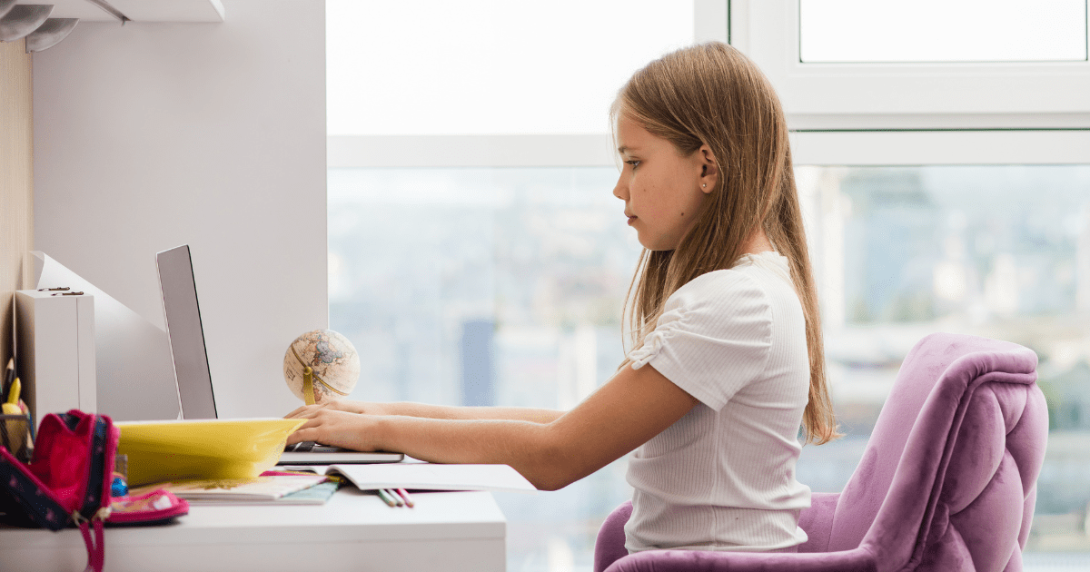 Young girl by her desk with an ergonomic chair and good posture with her computer