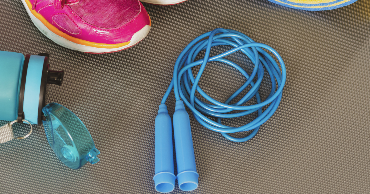 Photo of exercising equipment like water bottle, skipping rope, running shoes and a yoga mat for a healthy routine